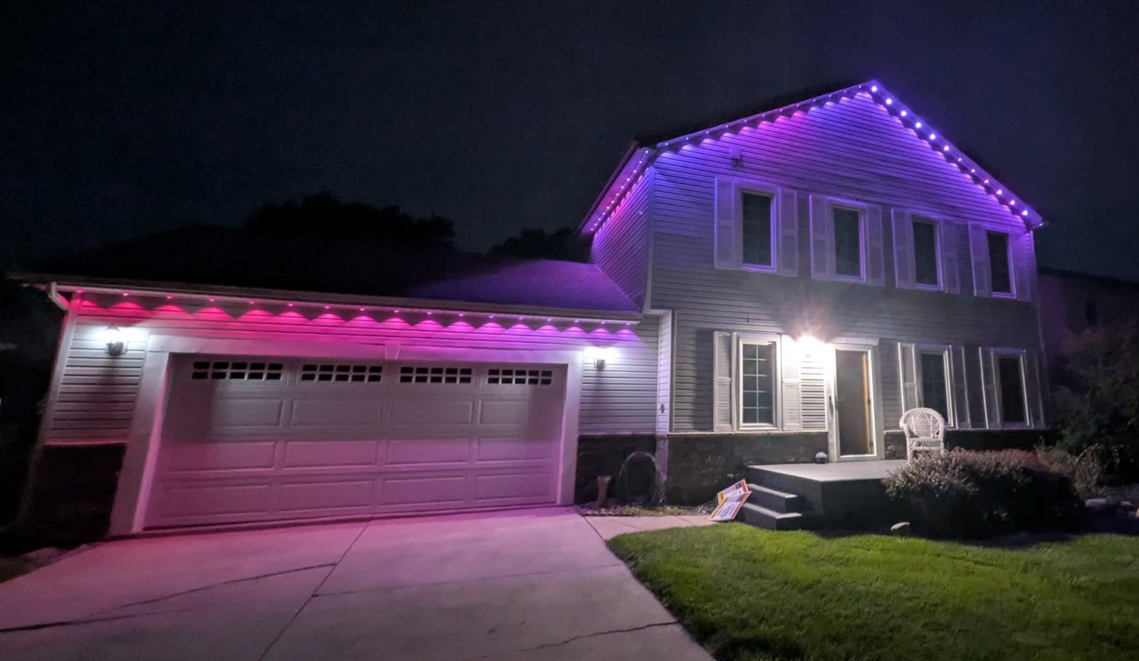 Home roofline lit in pink and purple with Govee permanent lights mounted in custom track