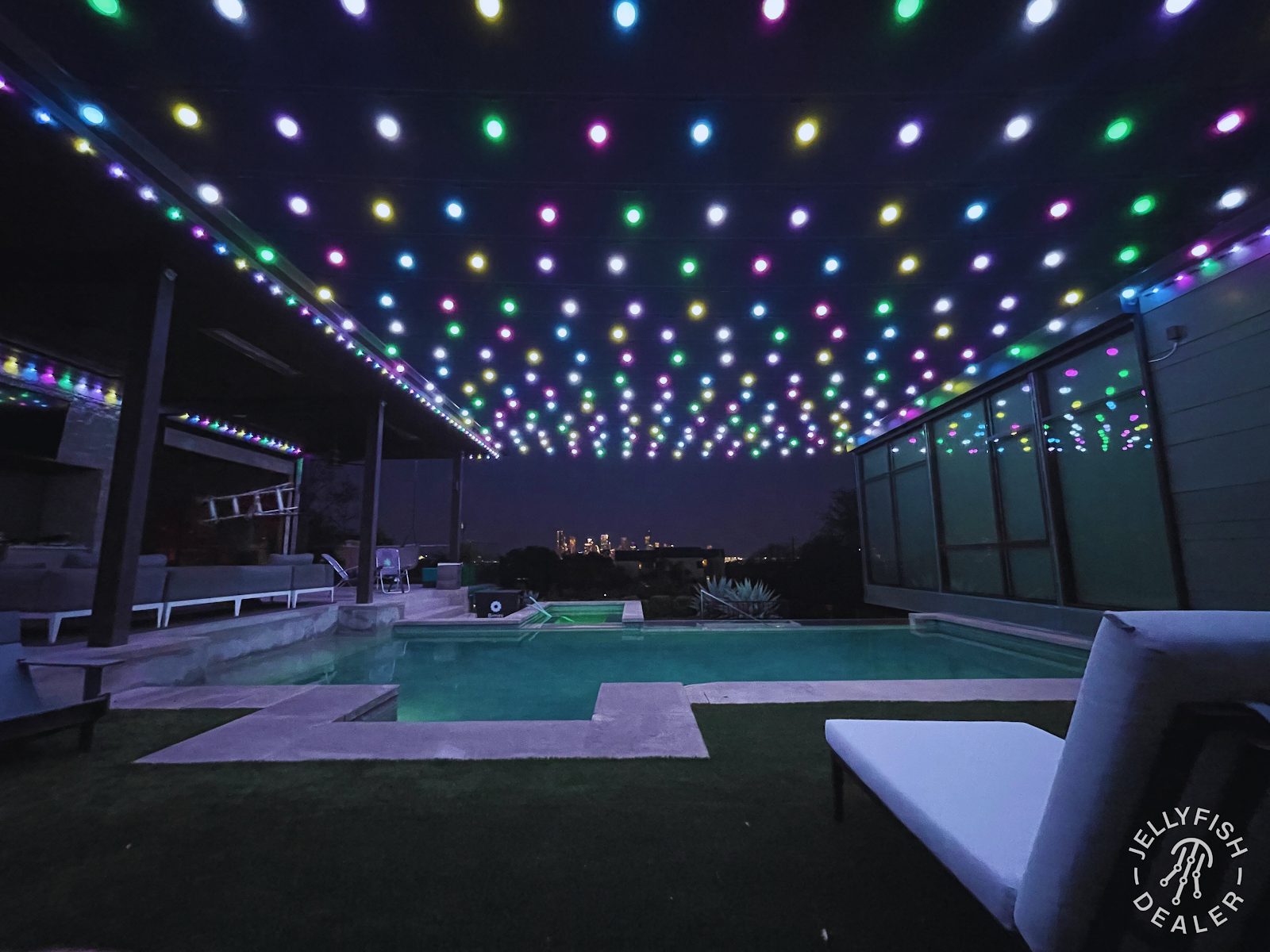 Outdoor kitchen and grill area lit with warm patio and accent lighting at night