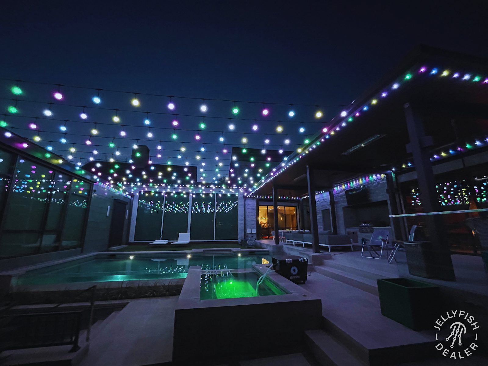 Backyard patio decorated with colorful party lighting for an evening gathering
