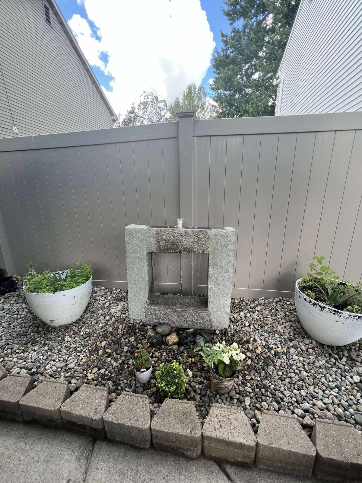 Mid-size bubbling water feature surrounded by landscaped plantings