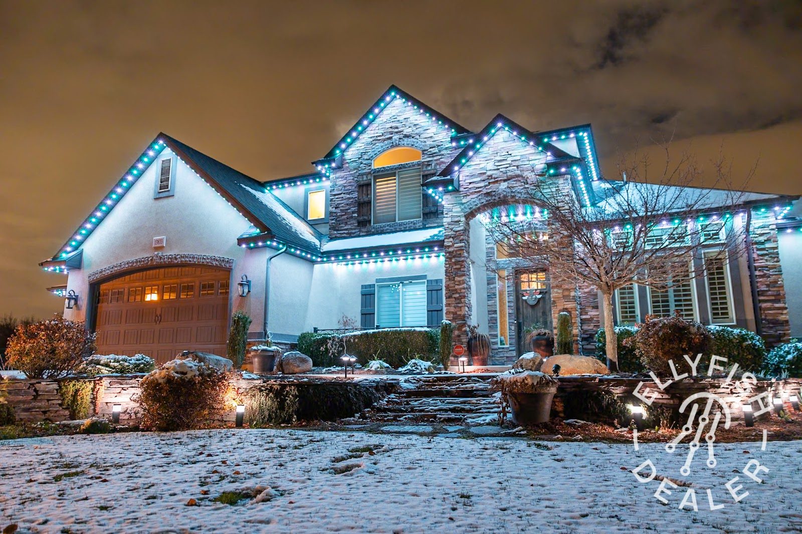 Landscape bed with layered uplighting on trees and stone edging at dusk