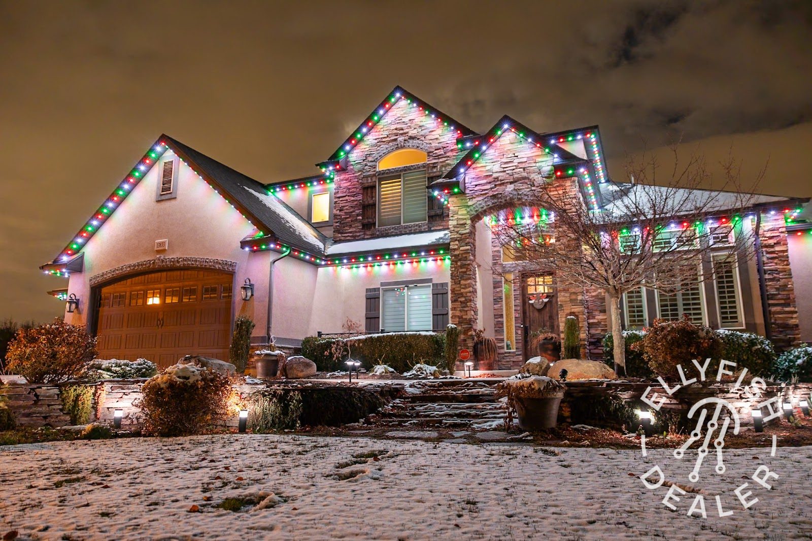 Home with layered permanent roofline and landscape lighting glowing at dusk