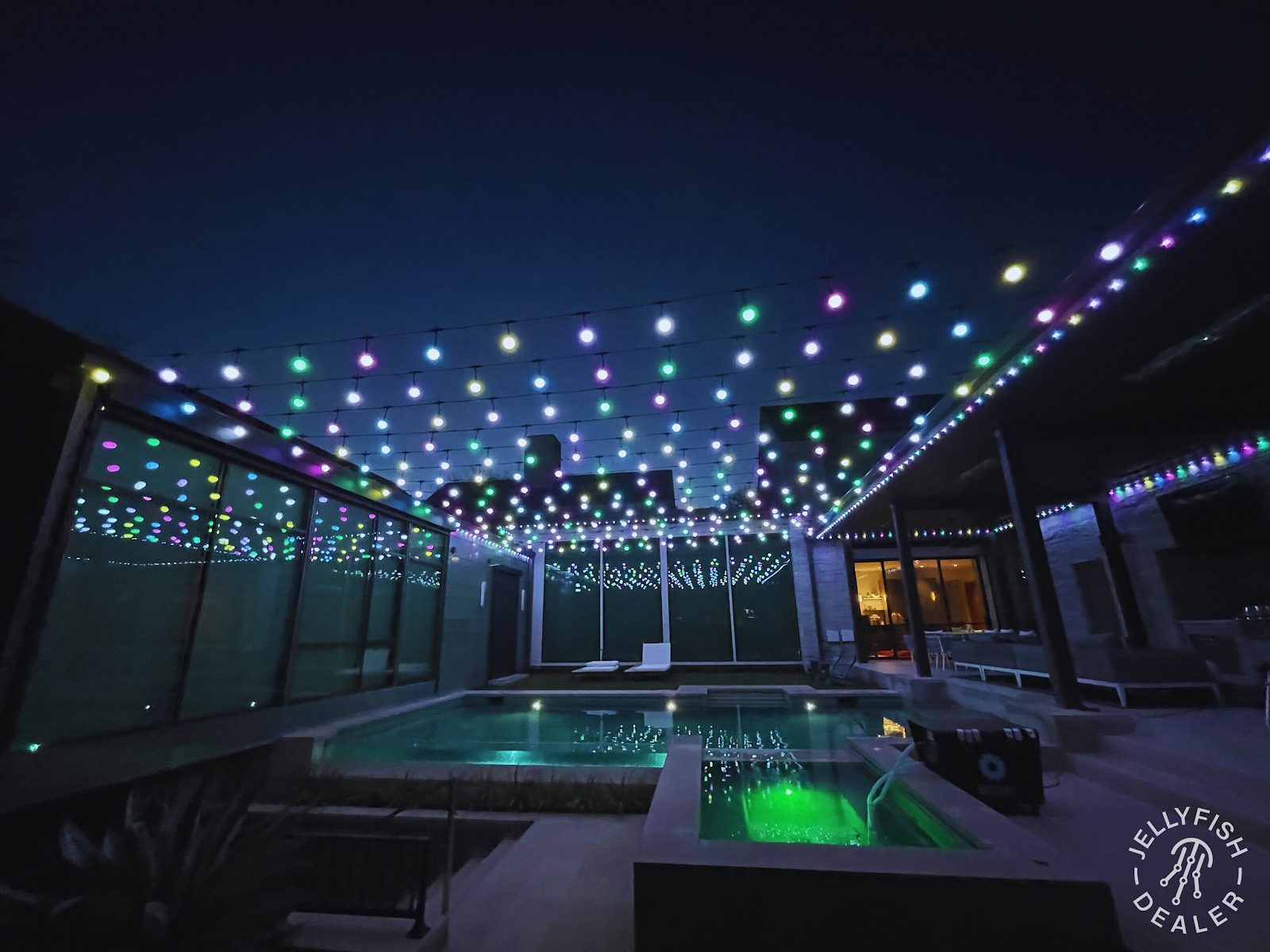 Warm white patio lighting strung above a backyard seating area at dusk