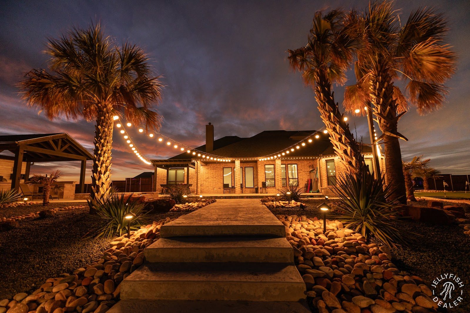 Patio string lights strung over a backyard party seating area at night
